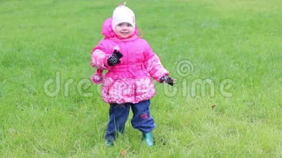 穿暖和衣服的小女孩站在草地上手挽手视频的预览图