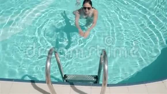 女孩从游泳池里出来了度假村里的夏日假日游泳的女孩在清澈的水潭里美丽视频的预览图