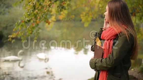 秋天漂亮的学生女孩在手机上聊天秋高气爽的高加索女人在智能手机上交谈视频的预览图