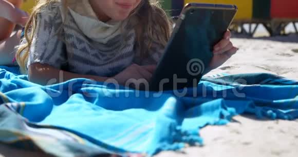 在海滩上使用数码平板电脑的女孩视频的预览图