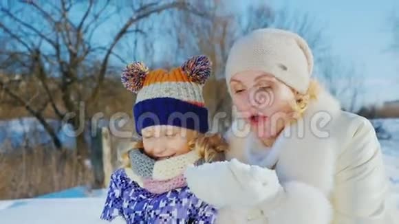 妈妈和她女儿玩了5年祝你度过美好的冬日把手中的雪吹掉视频的预览图