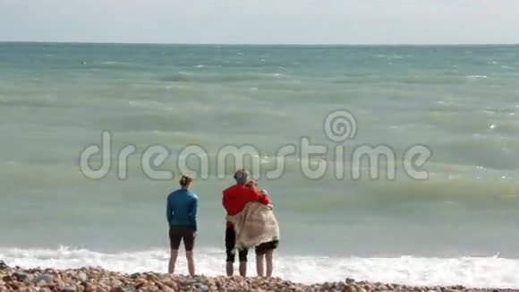 英国布莱顿年轻的夫妇和朋友在大西洋的岸边一对夫妇拥抱一个女孩站在一边视频的预览图
