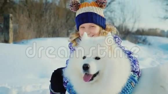 女孩5岁带着一只白色的毛茸茸的大狗在公园里玩冬天笑的女孩视频的预览图