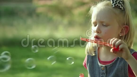 可爱的小女孩在夏天吹肥皂泡慢动作全高清视频的预览图
