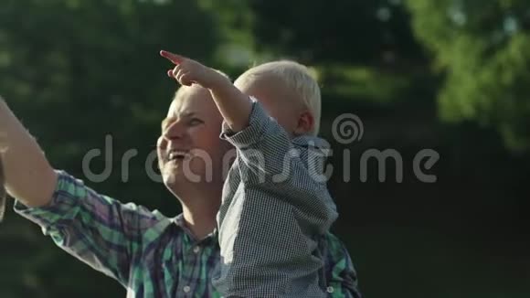 年轻的父亲和他的儿子在夏季公园慢动作全高清视频的预览图