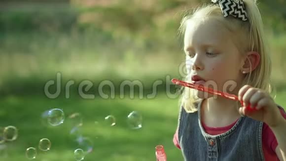 可爱的小女孩在夏天吹肥皂泡慢动作全高清视频的预览图