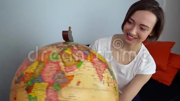 年轻女子转动地球仪仔细地看着它视频的预览图