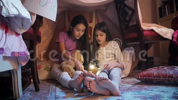 两个女孩在自制帐篷大声朗读书的4k视频视频的预览图