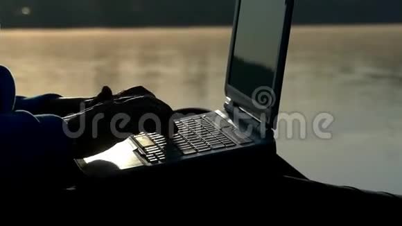日落时分女性手在笔记本电脑键盘上打字视频的预览图