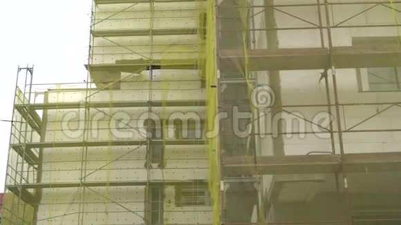 建筑外立面改造旧房改造修缮建筑正面覆盖黄色透明的脚手架视频的预览图