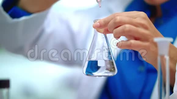 女化学家在玻璃瓶中加入化学试剂视频的预览图