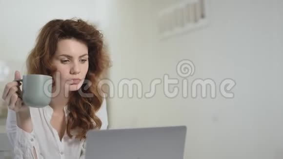 严肃的女人在开放式厨房看着笔记本电脑视频的预览图