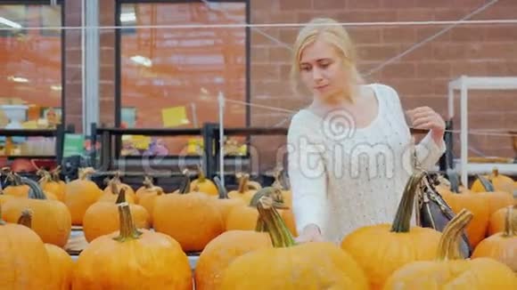 一个年轻的女人在一家大商店买南瓜它周围是柜台有大量的南瓜可供选择视频的预览图