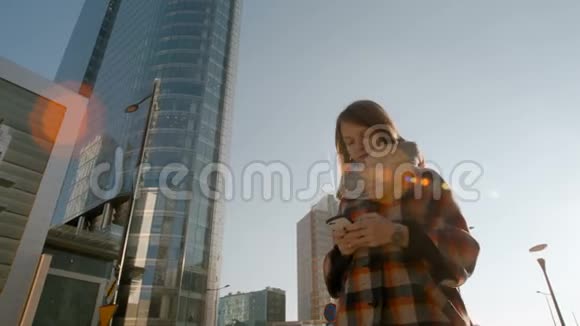 年轻女士在市中心散步用她的智能手机发短信视频的预览图