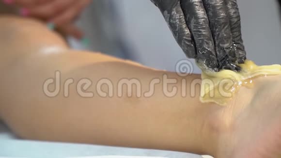 一个女人的手一个黑色的橡胶手套里用糖团把她脚上的头发撕下来做一个耸人听闻的慢动作视频的预览图