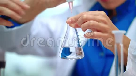 实验室研究人员双手将纯液体滴入实验室瓶中视频的预览图