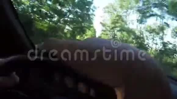 夏天一辆汽车穿过一条森林道路手躺在方向盘上视频的预览图