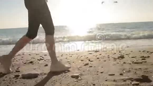 女人穿着跑鞋的腿沿着海滨海洋奔跑在海边奔跑视频的预览图
