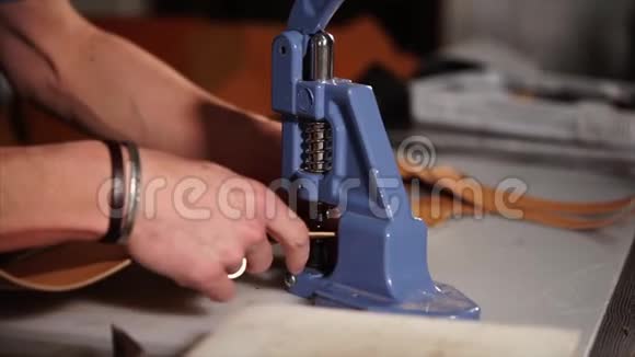 工匠用手压机在皮革上安装金属配件视频的预览图