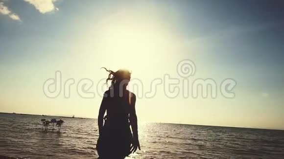 美丽的年轻女子在日落时在海滩上旋转慢悠悠地举起双臂享受自由视频的预览图