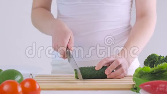 一个女人在厨房里切黄瓜准备一份美味的新鲜蔬菜沙拉作为午餐视频的预览图