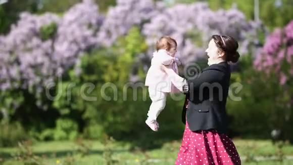 快乐的母亲和可爱的女婴一起在公园里玩反对花视频的预览图