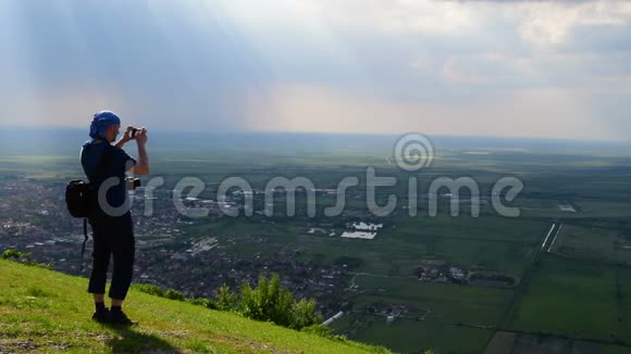 年轻人站在山上拍摄了一幅美丽的平原景色视频的预览图