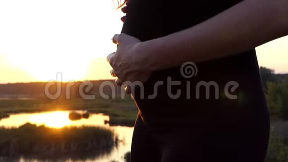 怀孕的女孩在日落时缓慢地跳舞和抚摸她的胃视频的预览图