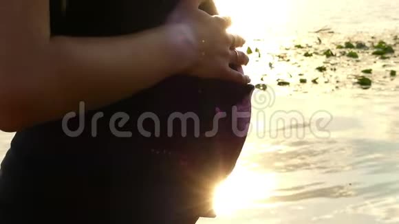 在斯隆莫的日落河畔女性手拍怀孕的肚皮视频的预览图