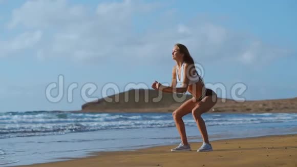 年轻美丽的女人在海滩上做运动日出早操健康的生活方式锻炼做仰卧起坐视频的预览图