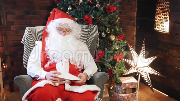 圣诞老人正在圣诞树附近读一封信视频的预览图