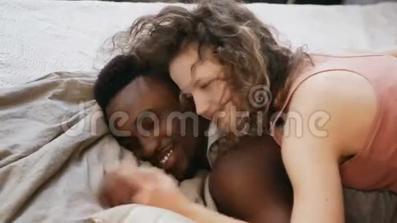 多民族夫妇浪漫的早晨女人躺在男人身上躺在床上拥抱男女谈话牵手视频的预览图