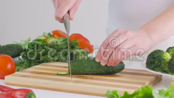 一个女人在厨房里切黄瓜准备一份美味的新鲜蔬菜沙拉作为午餐视频的预览图