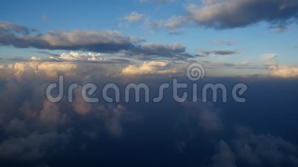 鸟瞰白色蓬松的云层日落时分在云层上方飞行从飞机的窗口观看云景视频的预览图