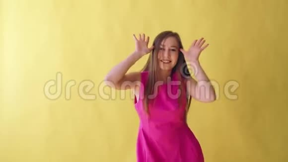 年轻迷人的成年女孩穿着黄色背景的粉色雅裙视频的预览图