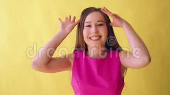 年轻迷人的成年女孩穿着黄色背景的粉色雅裙视频的预览图