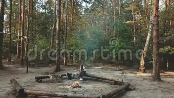 一个女孩坐在森林里看书女孩坐在火旁边的原木上看一本书鸟瞰视频的预览图