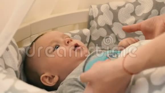 妈妈牵着一个小儿子的手把他放进婴儿床视频的预览图