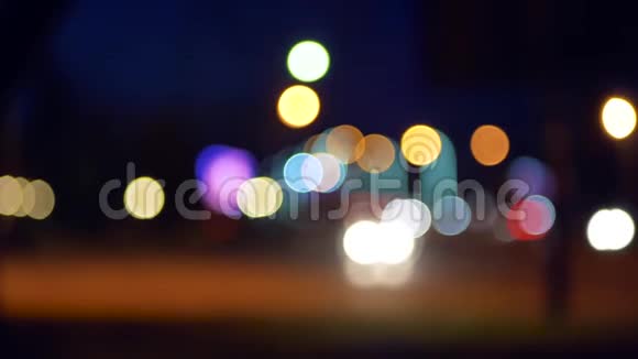 城市的夜间交通运动模糊在夜晚城市的背景上闪烁着彩色的灯光波克效应视频的预览图
