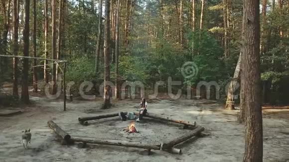 一个女孩坐在森林里看书女孩坐在火旁边的原木上看一本书鸟瞰视频的预览图