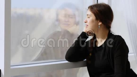迷人的年轻女子好奇地看着窗外看着镜头微笑视频的预览图