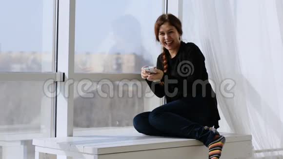 阳光明媚的一天一个女人坐在窗边笑着视频的预览图