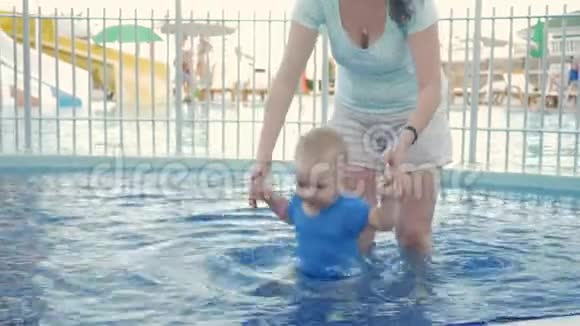 妈妈牵着一个孩子手在街上的游泳池里两岁以下的金发男孩视频的预览图