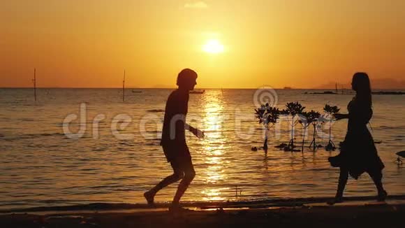 年轻夫妇互相跑去男人在美丽的夕阳下拥抱和旋转他的女人一起度假玩得开心视频的预览图