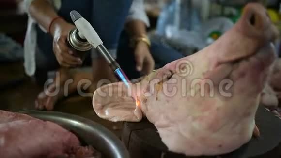高棉妇女用手电筒清洗一头被宰的猪头视频的预览图