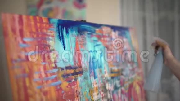 女艺术家在艺术工作室画一幅抽象画补漆艺术家把喷雾瓶洒在上面视频的预览图