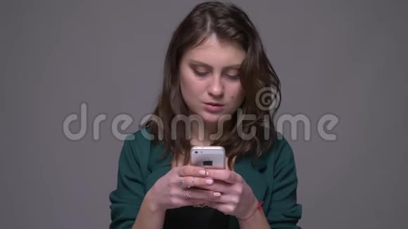 用手机和相机微笑背景与背景隔离拍摄一个有魅力的深色成年女性特写镜头视频的预览图