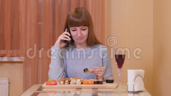 美女坐在寿司店里用她的智能手机视频的预览图