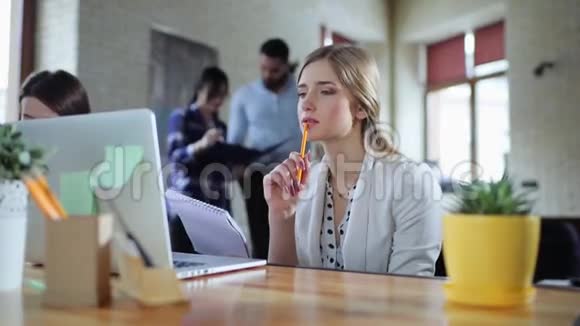 商务女性坐在办公室手提电脑和思考创业概念其他工人可以看到视频的预览图