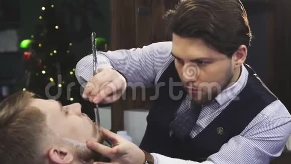 专业理发师用剃刀刮他的客户视频的预览图